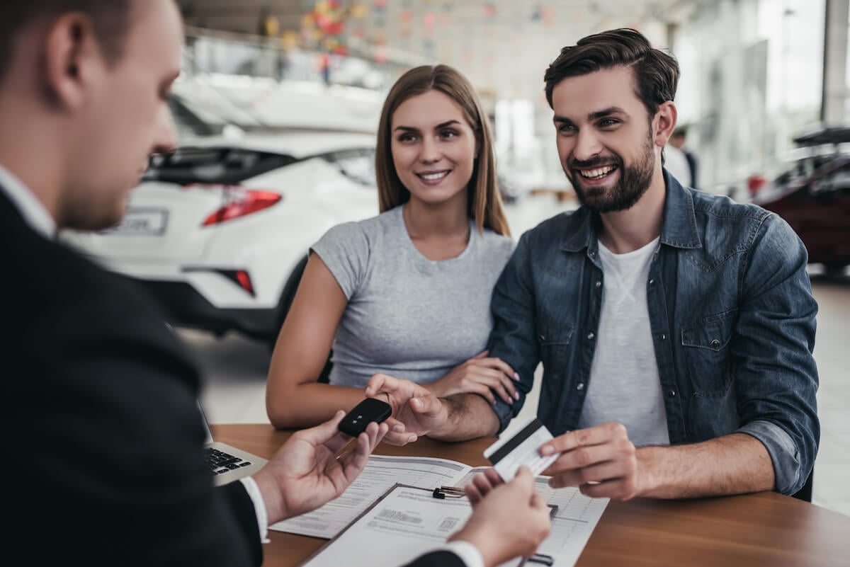 couple filling out finance paperwork at car dealership